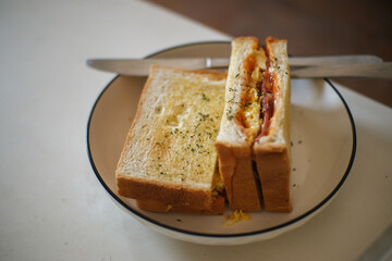 white bread with meat and egg filling spread with butter on a round plate on a minimalist table