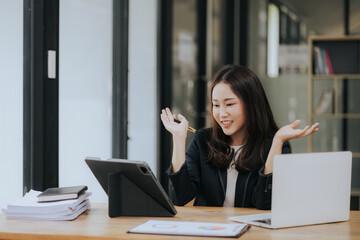 Asian businesswoman uses laptop to do finance, mathematics on office table, taxes, reports,...