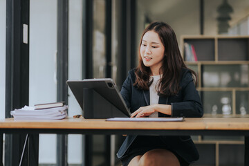 Asian businesswoman uses laptop to do finance, mathematics on office table, taxes, reports, accounting, statistics and analytical research concepts.