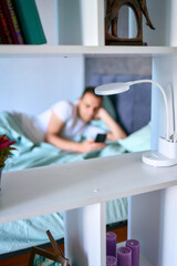 a young man scrolls in smartphone in the morning after waking up, morning routine