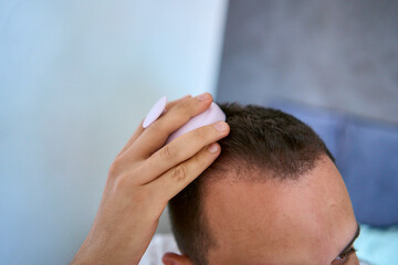 Fototapeta premium a man massages his head with an massager for hair growth