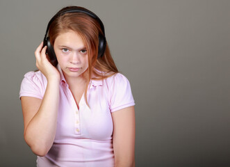 A girl wearing a pink shirt and headphones