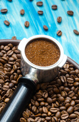 Coffee cone and ground coffee on coffee beans and on a ceramic plate.