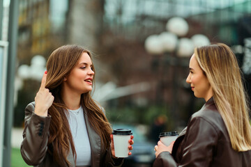 Two businesswomen enjoying a coffee break outside their office.