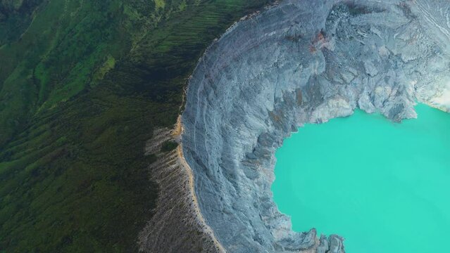 Top aerial view of turquoise sulfur water lake, surrounded by rock cliff at Kawah Ijen volcano in East Java, Indonesia.