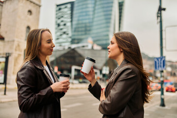 Two businesswomen enjoying a coffee break outside their office.