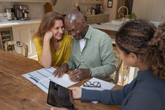 Happy senior couple signing a contract with their financial advisor