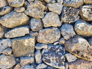 Rocks texture. Abstract background with dry round reeble stones. Stone wall exterior,background. Natural stone texture and background. Stone wall texture. Stone wall. Stone and texture. Small stones