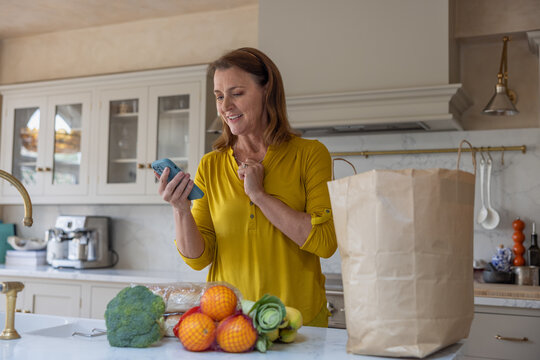 Senior woman checking grocery delivery on an app on a smartphone