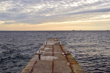 concrete pier, sea view, horizon, sky in clouds. empty concrete pier concept of rest, vacation, summer, trip to the sea, in Odessa. old pier. Image of an outfall with waves and clouds at sunrise