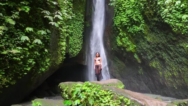 An exquisite and gorgeous Asian model is elegantly posing for a charming video shoot in front of the Leke Leke waterfall in Bali - Indonesia.