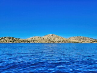 Sky with clouds. Yachts and boats in the sea. Pacific ocean. Cliffs and caves. View of the mountains from the sea. The circular coast, mediterranean sea. Seascape in blue. On a beautiful sunny day