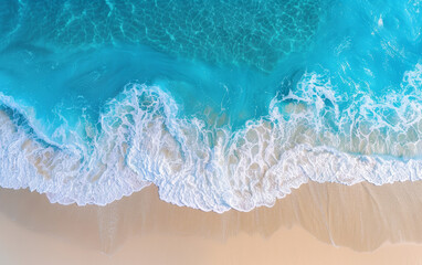 Aerial view of turquoise ocean waves crashing onto a sandy beach, capturing the natural beauty and tranquility of the coastline.