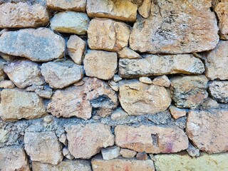 It made from little stones. Photo of old white stone wall texture background. Many rocks inside a...