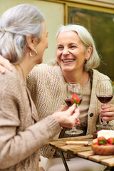 A lesbian couple enjoys a relaxing evening camping, laughing and sharing wine.