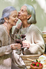 A lesbian couple enjoys a romantic moment while camping in a lush green forest. They share a glass...