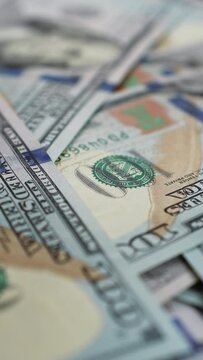 Hundred dollar bills falling on spinning table in a pile of cash. A heap of money growing larger and larger as additional banknotes raining down. Concept of business and finance