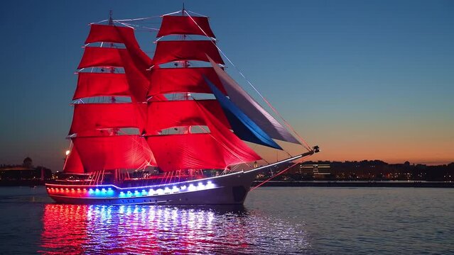 The sailing ship with scarlet sails floats on the Neva.  Brig with scarlet sails passes by on the background of the Peter-Pavel's Fortress. White night. Close up