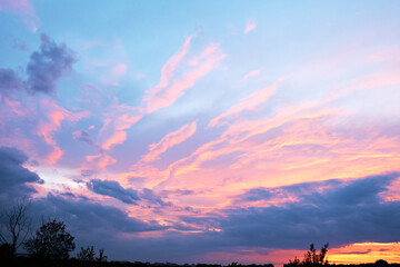 Fototapeta premium Dusk, sunset sky clouds in the evening with colorful orange, yellow, pink and red sunlight and dramatic storm clouds in the twilight sky, landscape horizon, nature, summer background.