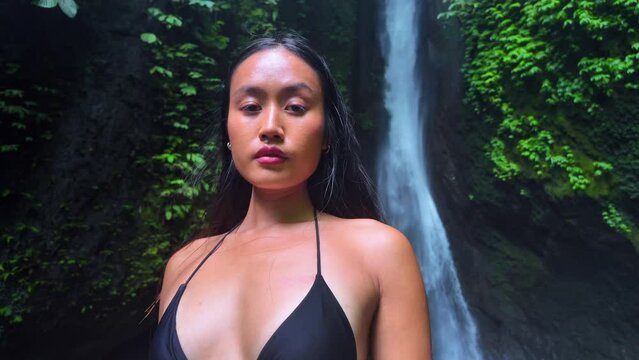 An exquisite and gorgeous Asian model is elegantly posing for a charming video shoot in front of the Leke Leke waterfall in Bali - Indonesia.