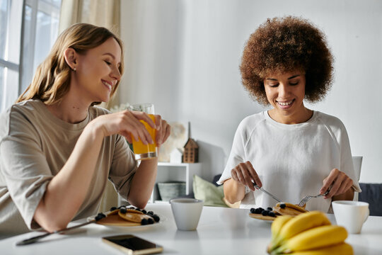 A diverse lesbian couple enjoys breakfast together at home.