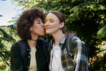 Fototapeta premium A young lesbian couple enjoys a hike in the woods, sharing a tender moment.