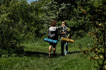 Two young women, a lesbian couple, hike together through a lush green forest.