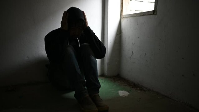 Asian man addict drug in the deserted place,A junkie feels alone in this world,Sad young man sitting in the corner of the room,People are stressed and have depression