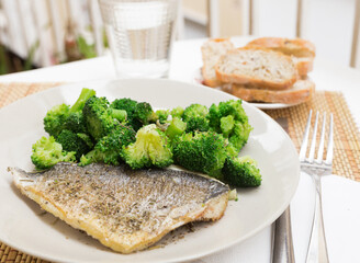 Dish of fried dorado fish fillet with boiled broccoli