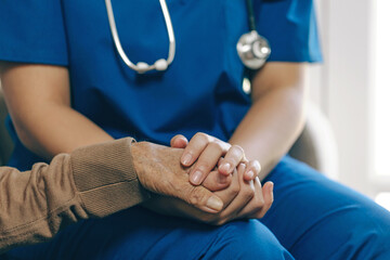 Female nurse holding her senior patient's hand. Giving Support. Female carer holding hands of...
