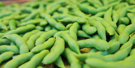 Many green edamame beans in pods as background, closeup,boiled green soybeans, Japanese beans