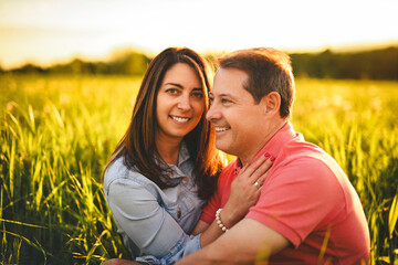 couple standing and hugging before a kiss against the background of the sunset in the field