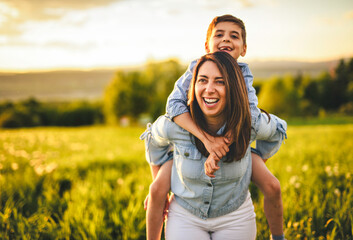 Fototapeta premium Beautiful mother with son on sunset field
