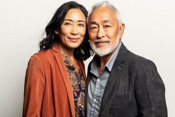 Fototapeta premium Portrait of a content mixed race couple in their 60s dressed in a stylish blazer in white background