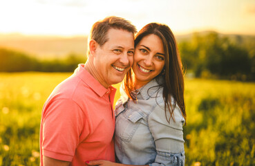 couple standing and hugging before a kiss against the background of the sunset in the field