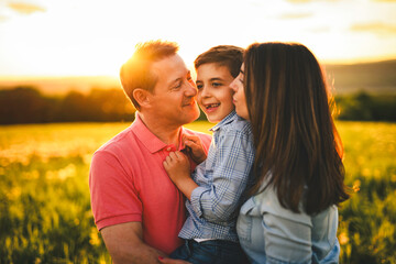 Beautiful father and mother with son on sunset field