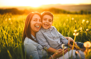 Beautiful mother with son on sunset field