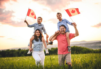 Adorable cute family holding Canadian flag on the shoulder