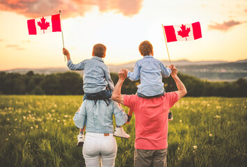 Adorable cute family holding Canadian flag on the shoulder