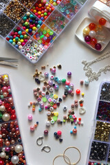Colorful beads, letter beads, threads and other jewelry making supplies on white background. Making...