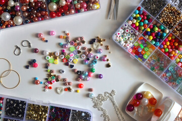 Colorful beads, letter beads, threads and other jewelry making supplies on white background. Making...