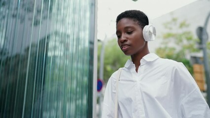 young charming Black woman in headphones, checks her smartwatch device with surprised expression as she rushes to work. Technology, modern city life and hustle of professional responsibilities
- Powered by Adobe