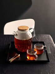 tea in a transparent teapot on the table on a dark background with smoke