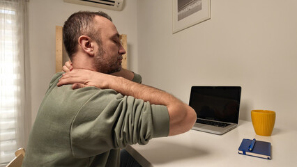 Man with neck pain while working on a laptop.
