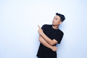 portrait of an Asian man pointing upwards. wearing a black t-shirt and a blue background.