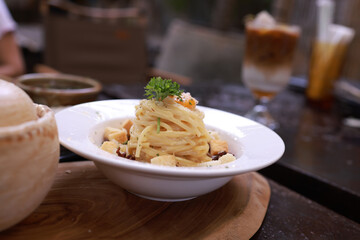 Coiled cooked Italian spaghetti topped with bread and seasoned with fresh chopped parsley and basil leaves Cream sauce spaghetti  in classic cup with prosciutto and parmigiano reggiano