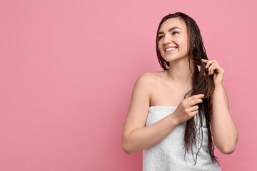 Young woman applying hair mask on pink background. Space for text