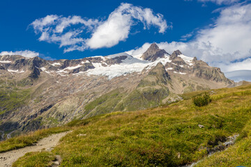 Fototapeta premium Tour du Montblanc beautiful mountain ladscapes of the Alps green valley, snow summit of Montblanc and rocky peaks of Aiguille du Midi in summer sunny weather blue sky, trekking and hiking in Chamonix