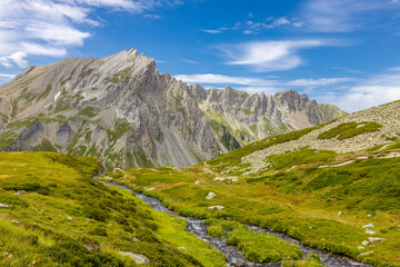 Obraz premium Tour du Montblanc beautiful mountain ladscapes of the Alps green valley, snow summit of Montblanc and rocky peaks of Aiguille du Midi in summer sunny weather blue sky, trekking and hiking in Chamonix