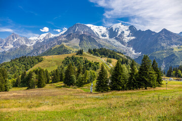 Tour du Montblanc beautiful mountain ladscapes of the Alps green valley, snow summit of Montblanc and rocky peaks of Aiguille du Midi in summer sunny weather blue sky, trekking and hiking in Chamonix